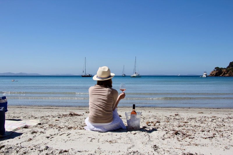 Woman drinking a glass of wine while sitting on a beach